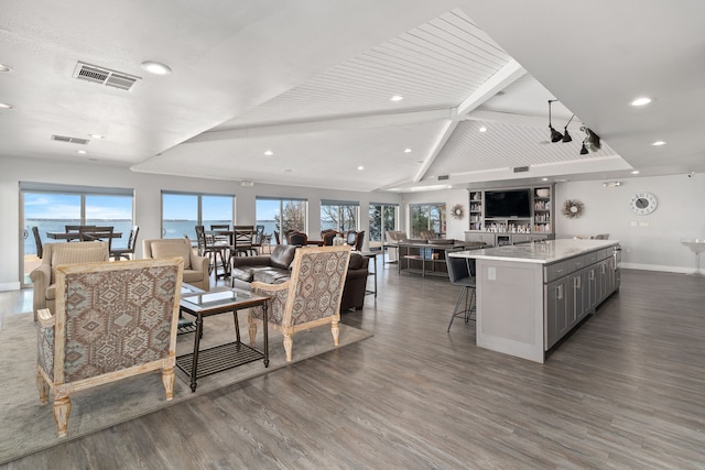 living room featuring dark hardwood / wood-style flooring, lofted ceiling with beams, and a healthy amount of sunlight