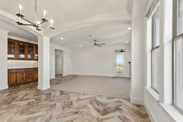 unfurnished living room featuring parquet flooring, ornamental molding, and ceiling fan with notable chandelier