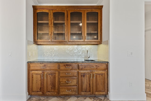 bar with decorative backsplash, dark stone counters, sink, and crown molding