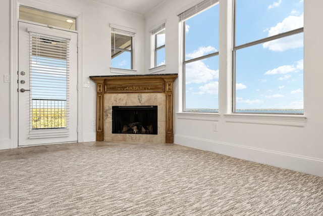 unfurnished living room featuring a premium fireplace, plenty of natural light, and crown molding