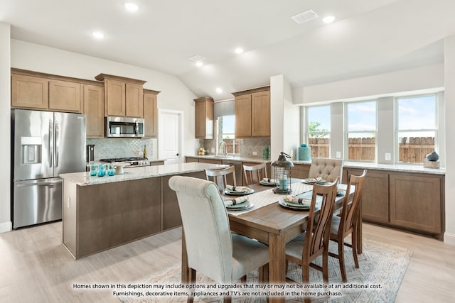 kitchen featuring stainless steel appliances, sink, light hardwood / wood-style flooring, and vaulted ceiling