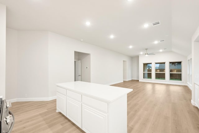 kitchen featuring visible vents, a center island, ceiling fan, white cabinetry, and light wood-style flooring