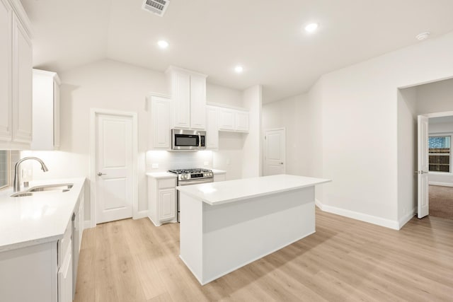 kitchen with light wood-style floors, tasteful backsplash, white cabinetry, appliances with stainless steel finishes, and a sink