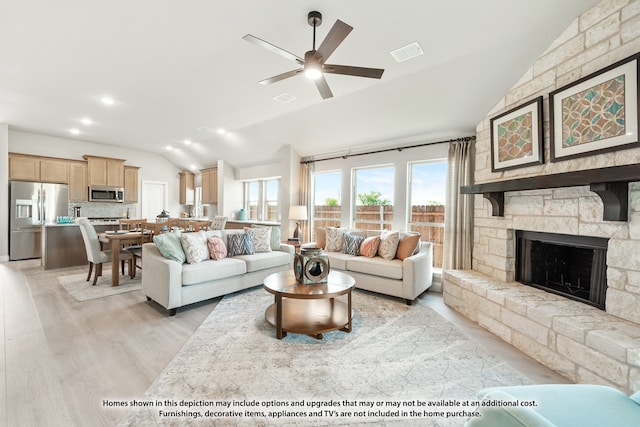 living room featuring light wood-type flooring, lofted ceiling, ceiling fan, and a fireplace