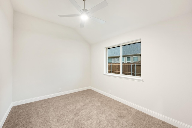 carpeted empty room with baseboards, a ceiling fan, and vaulted ceiling