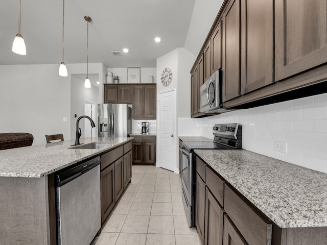 kitchen featuring stainless steel appliances, a center island with sink, decorative backsplash, sink, and pendant lighting