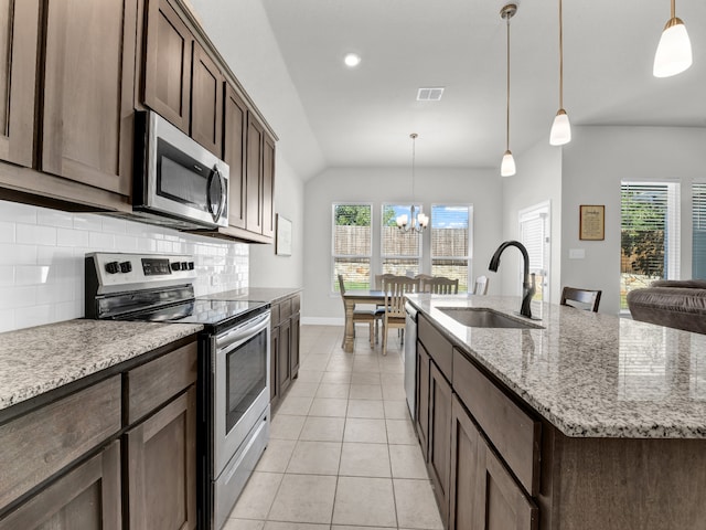 kitchen with a healthy amount of sunlight, appliances with stainless steel finishes, a kitchen island with sink, and sink