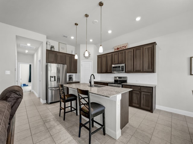 kitchen featuring stainless steel appliances, hanging light fixtures, sink, an island with sink, and a kitchen breakfast bar