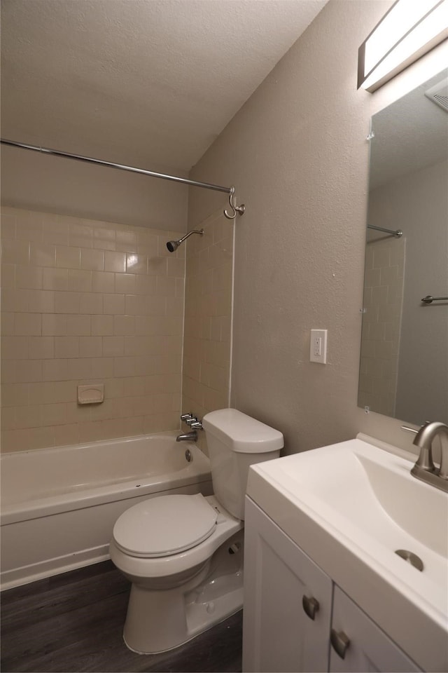 full bathroom featuring tiled shower / bath combo, wood-type flooring, a textured ceiling, toilet, and vanity