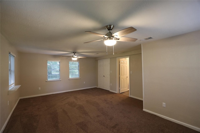 spare room featuring ceiling fan and dark carpet