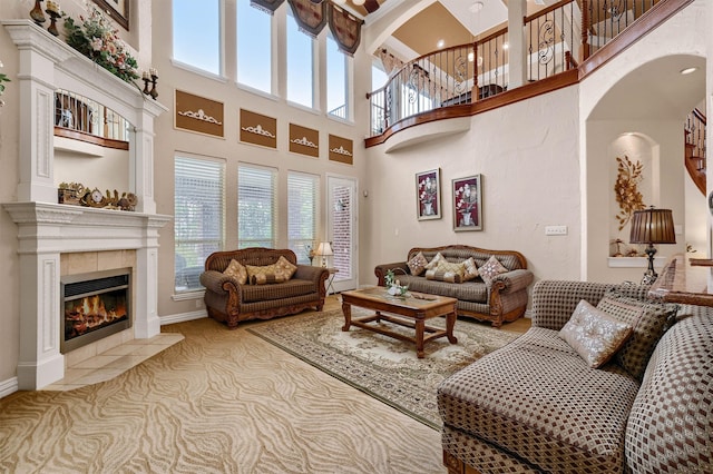 carpeted living room featuring a towering ceiling, a tiled fireplace, and a healthy amount of sunlight