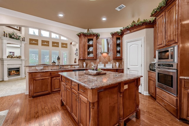 kitchen featuring ornamental molding, light wood-type flooring, stainless steel appliances, and a kitchen island