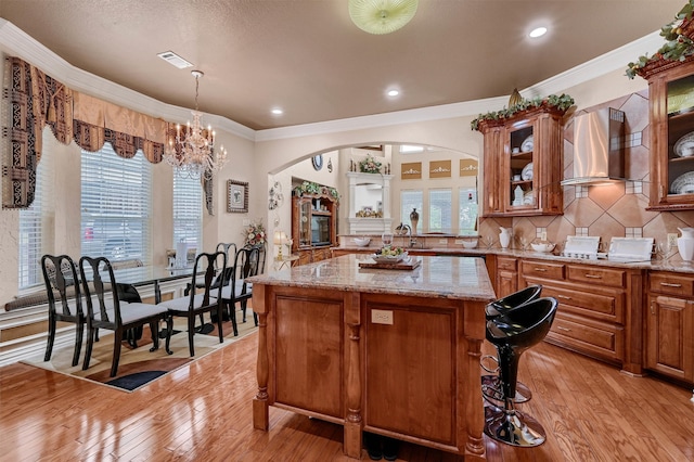 kitchen featuring ornamental molding, light wood-type flooring, a notable chandelier, and a center island