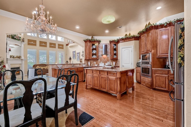 kitchen featuring stainless steel appliances, a kitchen island, light wood-type flooring, pendant lighting, and kitchen peninsula