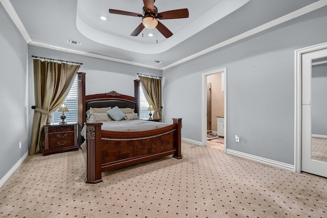 bedroom featuring ensuite bath, light carpet, ornamental molding, ceiling fan, and a tray ceiling