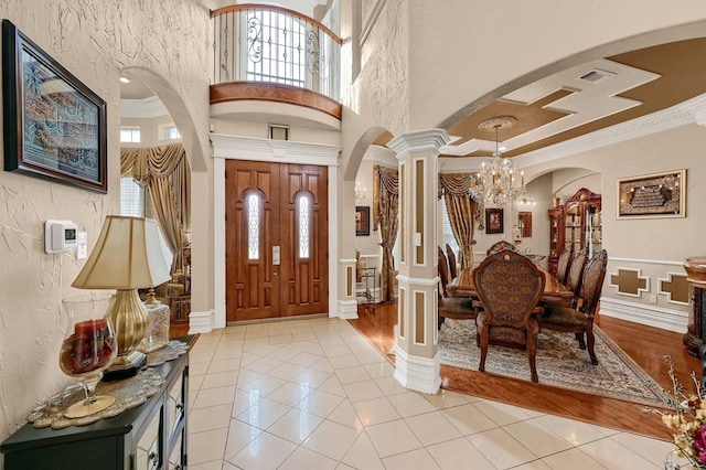 foyer with light hardwood / wood-style floors, a chandelier, ornate columns, and crown molding