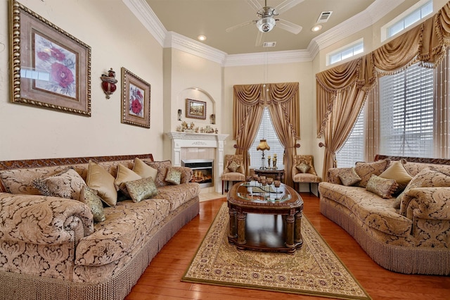 living room featuring hardwood / wood-style floors, ceiling fan, and crown molding