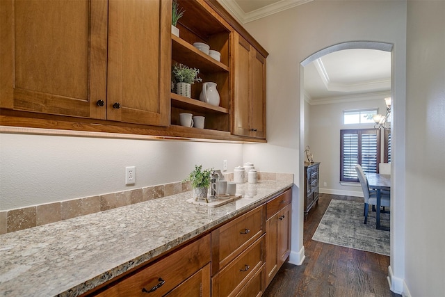 kitchen featuring dark hardwood / wood-style flooring, light stone counters, and crown molding