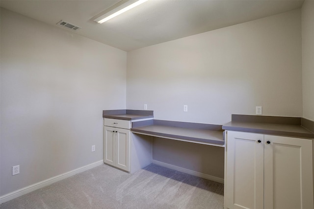 unfurnished office featuring built in desk and light carpet