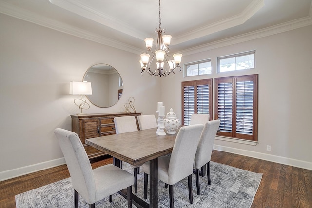 dining room with ornamental molding, a notable chandelier, dark hardwood / wood-style floors, and a tray ceiling