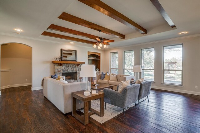 living room with crown molding, a fireplace, beam ceiling, dark wood-type flooring, and ceiling fan