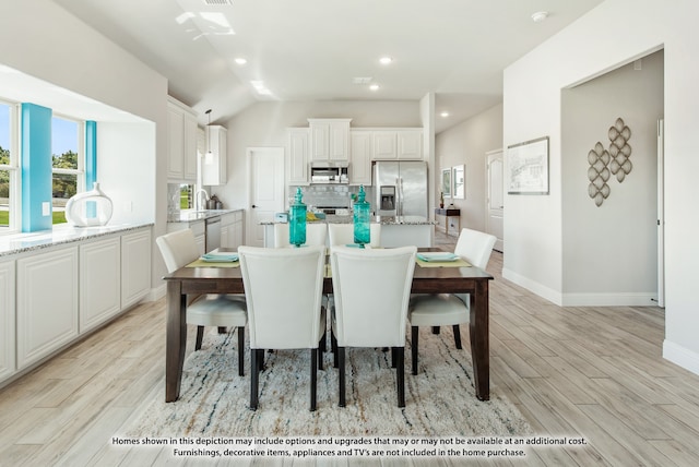 dining space with vaulted ceiling and light hardwood / wood-style floors