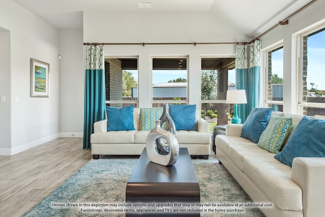 living room featuring a wealth of natural light, vaulted ceiling, and light hardwood / wood-style floors