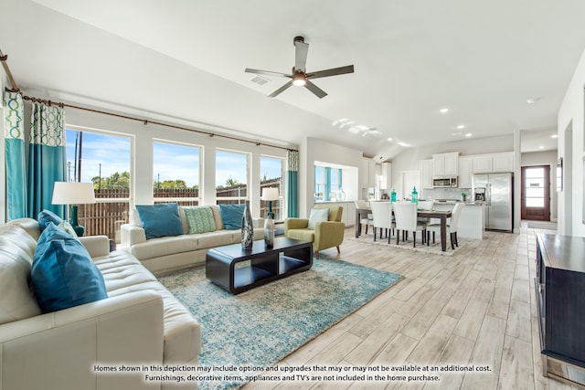 living room featuring ceiling fan, a healthy amount of sunlight, light wood-type flooring, and vaulted ceiling