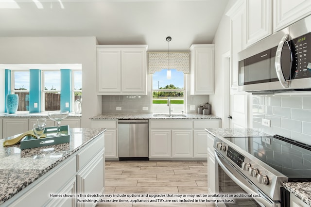 kitchen with white cabinetry, hanging light fixtures, sink, and stainless steel appliances