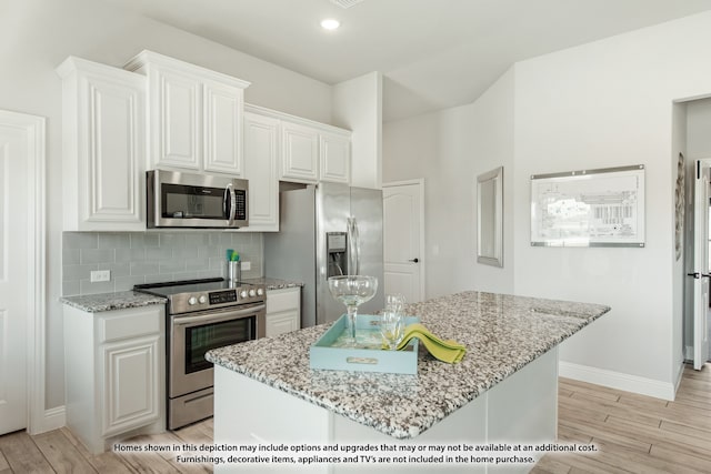 kitchen with white cabinetry, stainless steel appliances, light stone counters, and light hardwood / wood-style flooring