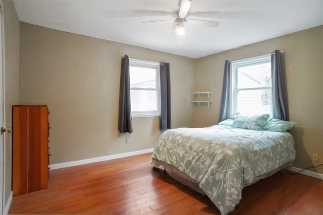 bedroom featuring multiple windows, hardwood / wood-style flooring, and ceiling fan