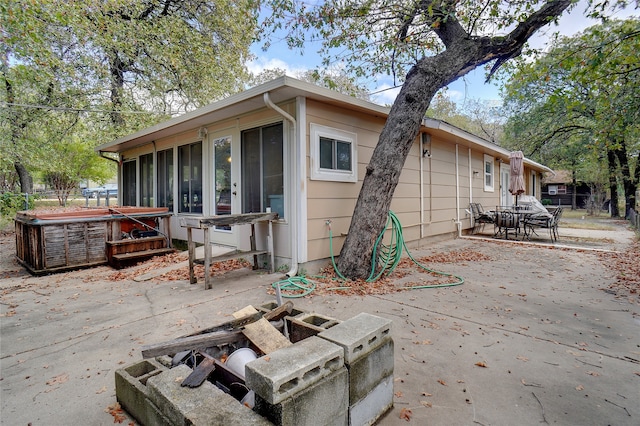 back of property featuring a hot tub, a patio, and a sunroom