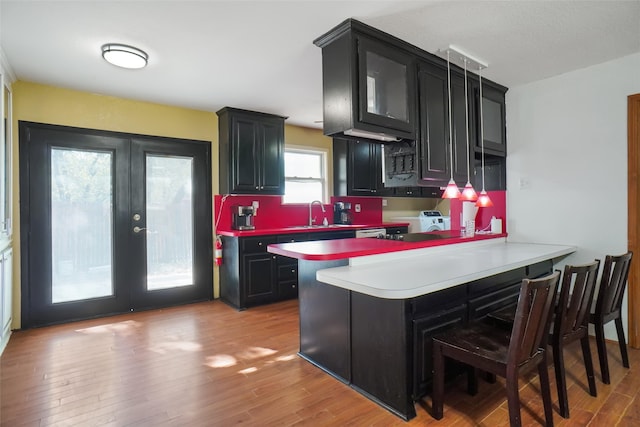 kitchen with french doors, a kitchen bar, light wood-type flooring, and kitchen peninsula