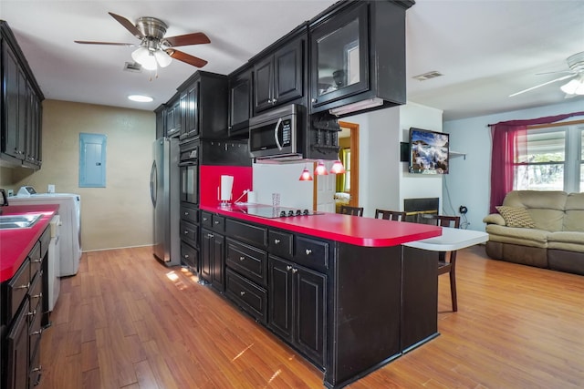 kitchen with light hardwood / wood-style flooring, black appliances, a breakfast bar area, and washer / clothes dryer