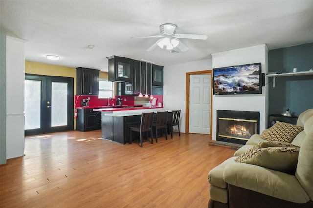 living room featuring french doors, light hardwood / wood-style flooring, sink, and ceiling fan