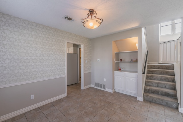 tiled empty room featuring a textured ceiling