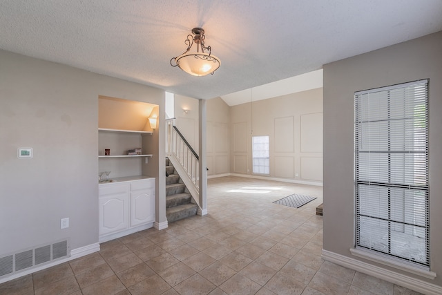 empty room featuring built in features, a textured ceiling, and light tile patterned floors