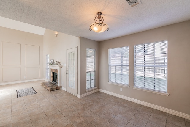 unfurnished living room with lofted ceiling, a textured ceiling, and light tile patterned floors