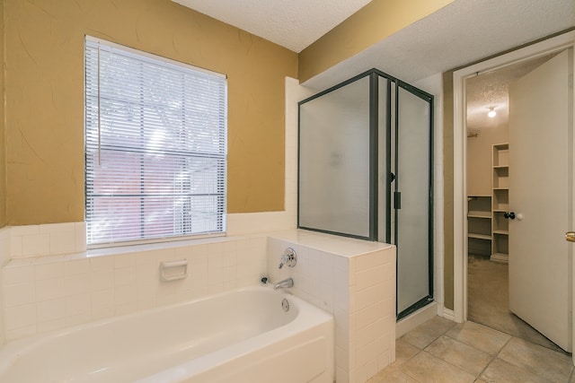 bathroom with a textured ceiling, tile patterned floors, and separate shower and tub