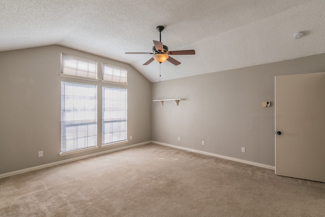 carpeted empty room with ceiling fan, a textured ceiling, and lofted ceiling