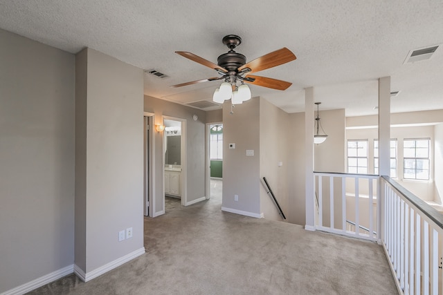 carpeted spare room featuring ceiling fan and a textured ceiling