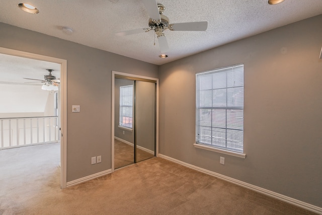 unfurnished bedroom featuring multiple windows, ceiling fan, carpet, and a closet