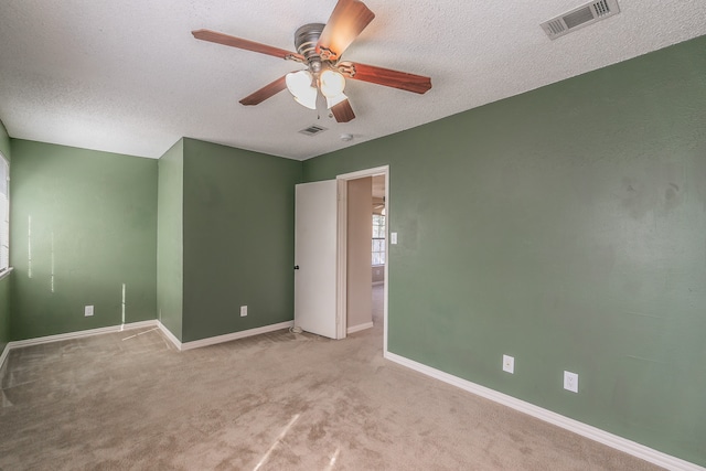 carpeted spare room featuring a textured ceiling and ceiling fan