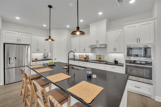 kitchen with stainless steel appliances, decorative backsplash, sink, white cabinetry, and decorative light fixtures