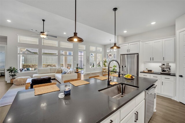 kitchen with stainless steel appliances, wood-type flooring, sink, and pendant lighting