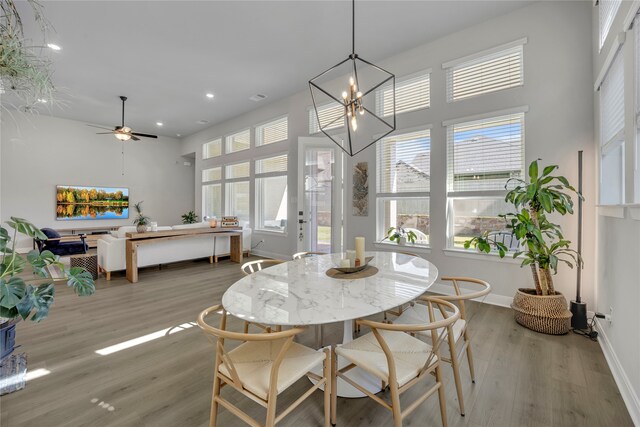 dining space with hardwood / wood-style floors, ceiling fan with notable chandelier, and plenty of natural light