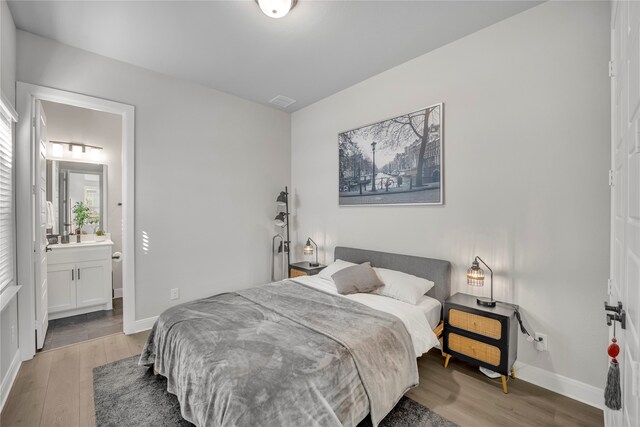 bedroom with wood-type flooring and connected bathroom