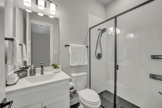 bathroom with walk in shower, vanity, and toilet