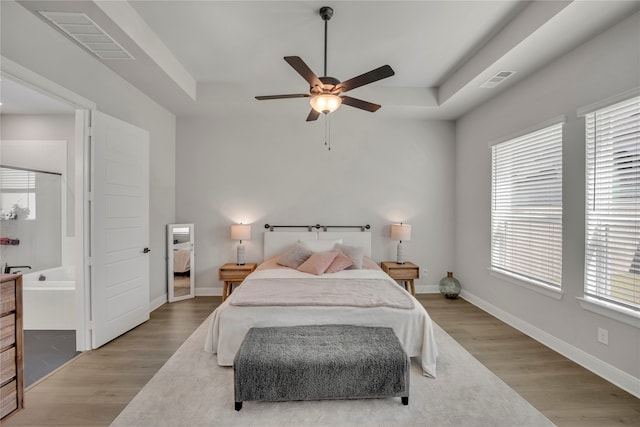 bedroom with ensuite bathroom, light hardwood / wood-style floors, and ceiling fan