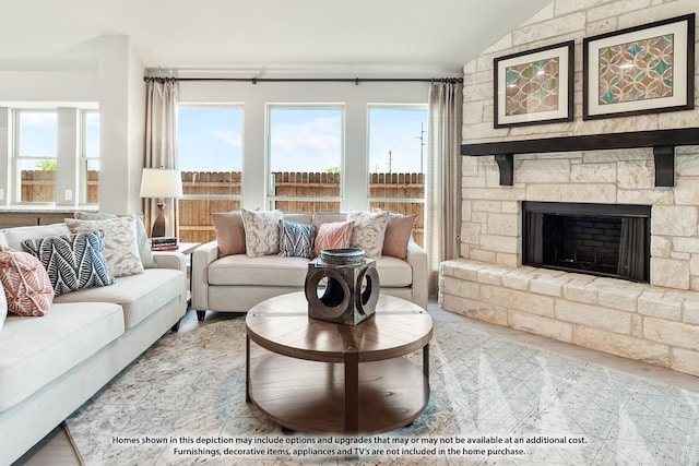 living room featuring a stone fireplace and vaulted ceiling